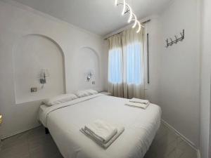 ein weißes Schlafzimmer mit einem großen Bett mit Handtüchern darauf in der Unterkunft Apartamento A Frente del Canal con Terraza in Empuriabrava
