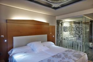 a bedroom with a white bed with a wooden headboard at Hotel Sancho Abarca Petit SPA in Huesca