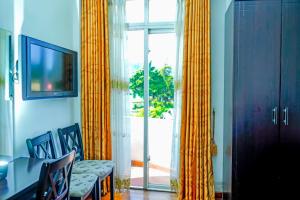 Habitación con cortinas y sillas amarillas y ventana en Mountain Breeze Apartment, en Nuwara Eliya 4 fotos más
