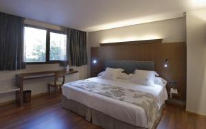 a hotel room with a large bed and a desk at Hotel Sancho Abarca Petit SPA in Huesca