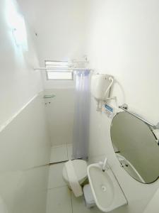 a white bathroom with a toilet and a mirror at Vilare Pousada in Morro de São Paulo