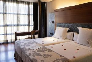 a bedroom with a large bed with red flowers on it at Hotel Sancho Abarca Petit SPA in Huesca