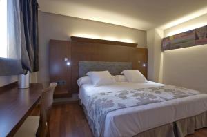 a bedroom with a large bed and a desk at Hotel Sancho Abarca Petit SPA in Huesca