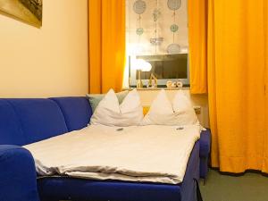 a bed with white pillows on a blue couch at Strandburg-Küken in Fehmarn