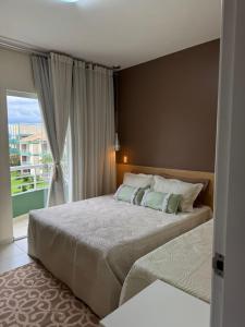 a bedroom with two beds and a large window at Aldeia das águas Park Resort - Flat D308 Village das Águas in Barra do Piraí