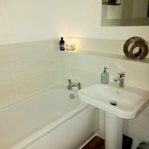 a white bathroom with a sink and a bath tub at Modern, chic 3-storey town house in Runcorn
