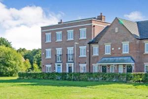 a large brick building with a grass field in front of it at Modern, chic 3-storey town house in Runcorn
