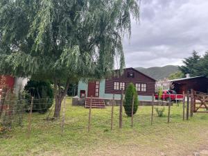 a fence in front of a house with a tree at Cabaña Sol&Luna in Tafí del Valle