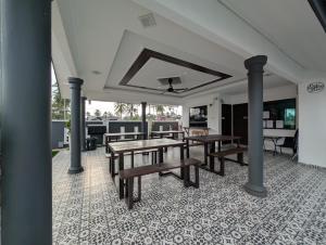 a patio with wooden tables and chairs on a tile floor at Flouzan Villa in Setiu
