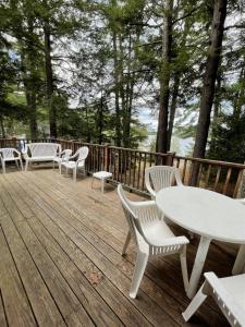 a deck with white tables and chairs and trees at SUNSET HAVEN LIMIT 8 cottage in Gray