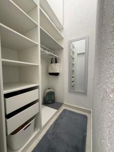 a walk in closet with white shelves and a mirror at Apartment4you in Senj