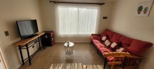 a living room with a red couch and a television at Casa Fundadores in Puerto Montt