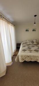 a bedroom with a bed and white curtains at Casa Fundadores in Puerto Montt