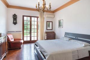 a bedroom with a bed and a chair and a chandelier at Casa degli Zii appartamento Letizia in Luni
