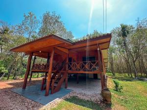 una piccola casa in legno con una terrazza in un campo di Bann Koh Pu Homestay a Ban Klang