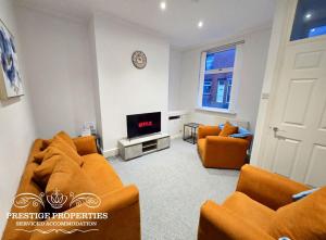 a living room with two orange couches and a tv at 31 Westmorland Street by Prestige Properties SA in Barrow in Furness