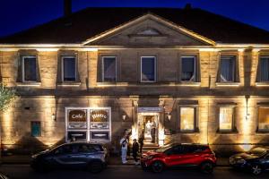 ein Gebäude mit davor geparkten Autos in der Unterkunft Fränkischer Hof in Mainleus