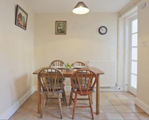 a dining room table with three chairs and a clock on the wall at 1a Park Lane in Southwold