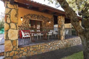 a stone house with a table and chairs on a balcony at Preciosa villa rural a poca distancia de Ávila by Alterhome in Velayos
