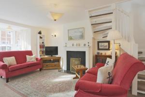 a living room with two red chairs and a fireplace at 1a Park Lane in Southwold