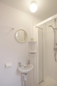 a white bathroom with a sink and a mirror at 1a Park Lane in Southwold +10 photos
