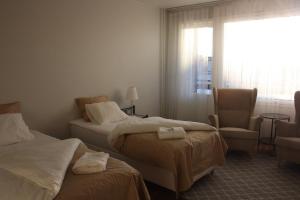 a hotel room with two beds and a chair and a window at BlueSolarPearl T - More than a hotel in Nokia