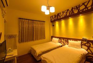 2 camas en una habitación con paredes amarillas en Summer Travel B&B en Taitung