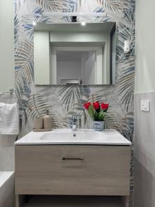 a bathroom with a sink and a mirror and red roses at Il Tulipano house in Catania