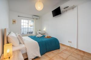 a white bedroom with a bed and a television at Bright & Cozy House with Terrace by HostWise in Conceição