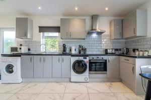 a kitchen with white cabinets and a washer and dryer at The Hawton House in Nottingham