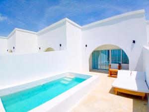 a white house with a swimming pool and a chair at Le Saint Tropez in Kidoti