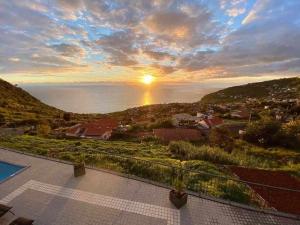 a view of the sunset from the balcony of a house at Shangri Sol - Holiday house in Arco da Calheta