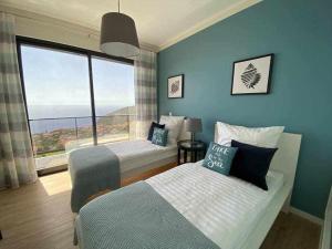 a bedroom with two beds and a large window at Shangri Sol - Holiday house in Arco da Calheta +10 photos