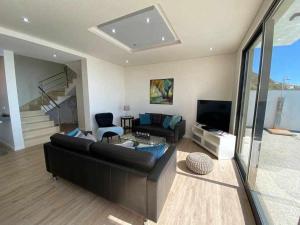 a living room with a couch and a television at Shangri Sol - Holiday house in Arco da Calheta