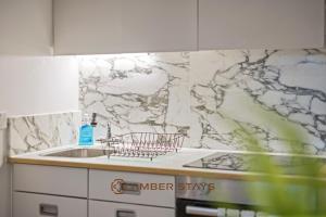 a kitchen with a sink and a marble wall at Modern 2 Bed Apartment in Greenwich, Perfect for Business & Contractors with Free Parking! in London +26 photos