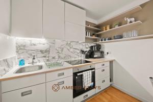 a kitchen with white cabinets and a sink at Modern 2 Bed Apartment in Greenwich, Perfect for Business & Contractors with Free Parking! in London