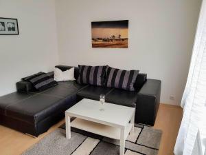 a black leather couch in a living room with a table at Ferienwohnung Amelie in Ribnitz-Damgarten