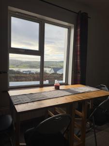 a table with chairs and a large window at Trábréaga Cottage in Ballyliffin