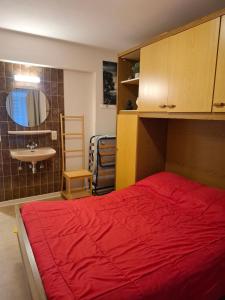 a bedroom with a red bed and a sink at Appartement Jupiter 3E Sea View in Blankenberge