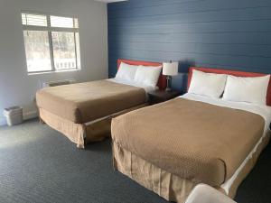 two beds in a room with blue walls at Flagship Inn in Boothbay Harbor +43 photos