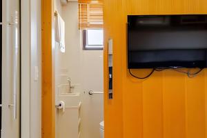 a bathroom with a flat screen tv on a orange wall at Golden Ingá Hotel Flat in Maringá