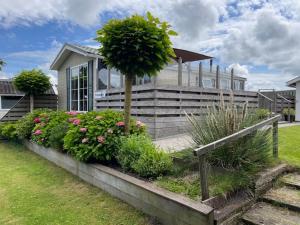 una casa con un albero e dei fiori davanti di Chalet Makkum C99B met prive gelegen tuin aan het water a Makkum