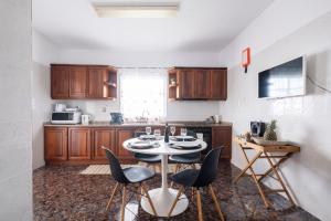 een keuken met houten kasten en een tafel en stoelen bij De Casa Villa by GALMI in Estreito da Calheta