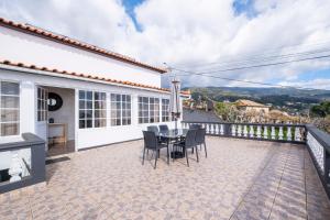 een terras met een tafel en stoelen op een balkon bij De Casa Villa by GALMI in Estreito da Calheta