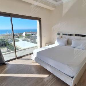 una camera da letto con un grande letto bianco e una grande finestra di Thé Blue Pearl Villa Ocean View Taghazout Bay Amda a Taghazout Altre 44 foto