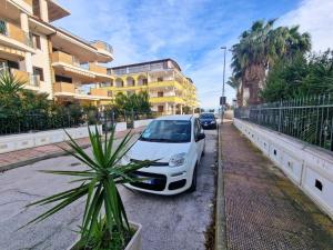 een witte auto geparkeerd op een parkeerplaats naast een gebouw bij Casa Vacanza Viale Italia in Vieste +3 foto's