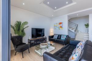 ein Wohnzimmer mit Sofa, Sesseln und Fernseher in der Unterkunft Ocean and Palms in Arco da Calheta