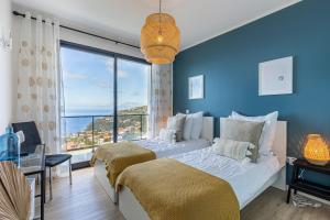 ein blaues Schlafzimmer mit 2 Betten und einem großen Fenster in der Unterkunft Ocean and Palms in Arco da Calheta + 25 Fotos
