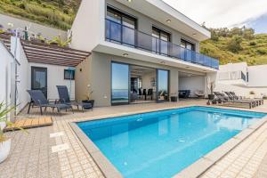 eine Villa mit Swimmingpool und ein Haus in der Unterkunft Ocean and Palms in Arco da Calheta