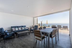 ein Esszimmer mit Tisch und Stühlen und dem Meer in der Unterkunft Ocean and Palms in Arco da Calheta